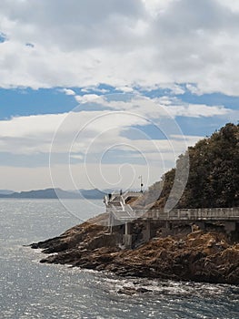 Long pier with stairs in mountains by sea under cloudy sky in Tsitsikamma Village, South Africa