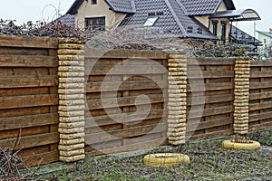 long private brown fence on a rural street made of wooden boards and bricks