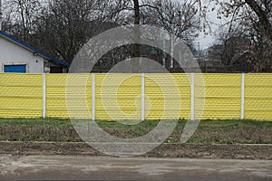 Long private concrete yellow fence on a rural street