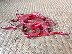 Long red arbol chilies on a woven pandan leaf mat