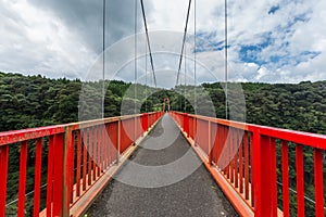 long red bridge and forest with cloudy sky background in Kamikawa Otaki Waterfall Park, Kagoshima, Kyushu, Japan