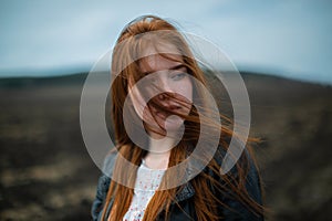 Long red hair covers the face of a young girl with freckles.