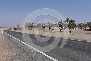A long road alongside red dirt desert at outback rural of New South Wales, Australia.