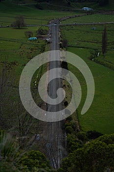 a long road going past a lush green field of trees