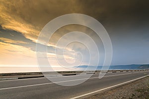 Long road and sea, lake or ocean line in sunset