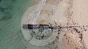 Long, rocky wave breaker on the beach with calm waves crashing against it on a Summer`s day at Point Lonsdale, Mornington