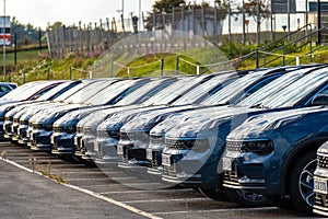 Long row of black cars ready for delivery at a car dealership..