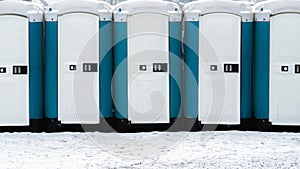 Long row of mobile toilets outside on the snowy ground. Bio toilets outdoors