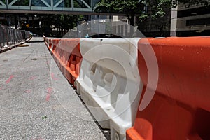 Long row of orange and white plastic traffic barricades dividing an asphalt street in an urban setting