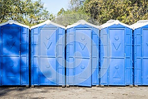 Long row of portable bio toilet cabins. Blue cabines of bio toilets. A large number of street toilets