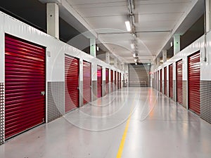 Long row of red color doors of self storage facility. Service to keep safe extra belongings. Nobody. Selective focus. Clean and