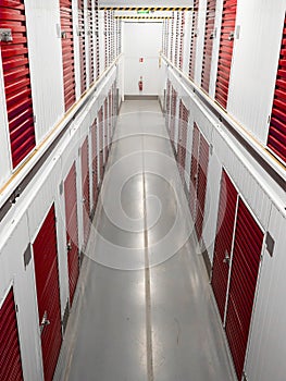 Long row of red color doors of self storage facility. Service to keep safe extra belongings. Nobody. Selective focus. Clean and