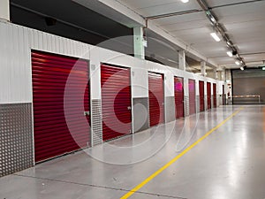 Long row of red color doors of self storage facility. Service to keep safe extra belongings. Nobody. Selective focus. Clean and