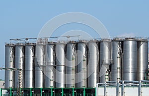 Long row of stainless storage silos for liquids and differents types of free flowing raw materials