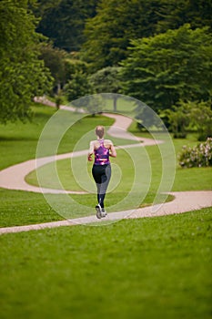 In it for the long run. Rearview shot of a woman jogging along a foothpath in a park.