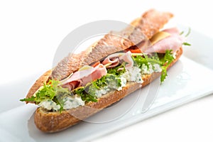 Long sandwich with ham, cheese, tomatoes and lettuce. Isolated on white background