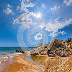 long sandy sea beach with hude stones at hot sunny day