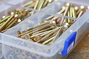 Long self-tapping screws in transparent plastic storage box on a wooden bench