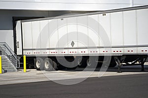 Long semi trailer loading industrial cargo in warehouse dock wit