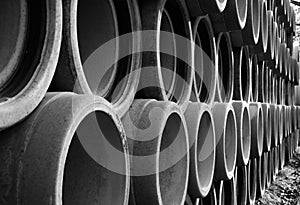 Long series of stacked reinforced concrete pipes in black and white 2