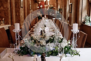 Long served table in the restaurant with many transparent glasses, napkins and tableware decorations