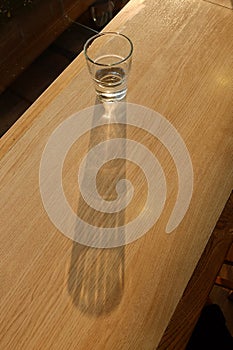 Long shadow of water glass on wood table