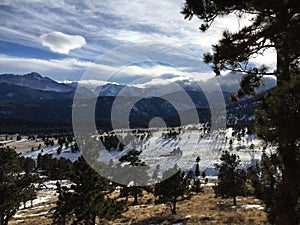 Long shadows and clouds over snow capped mountain peaks.