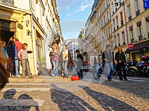 Long shadows on cobbles street and tourists on street corner in Montmartre district