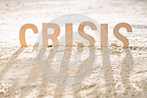 Long shadows from the word crisis bogged down in the sand