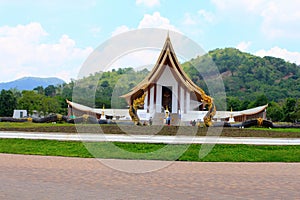 Long shot of a beautiful white Buddhist temple with dragon fountains at Ban Nong Chaeng,