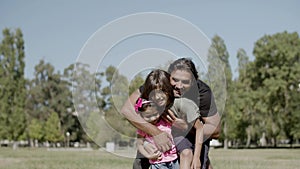 Long shot of disabled father hugging daughter and son in park