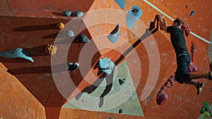 Long shot a male professional climber trains on an artificial wall in the gym