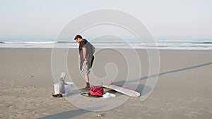Long shot of man with artificial leg suiting up on ocean coast