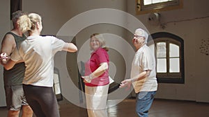 Long shot of senior couples having dance class in ballroom