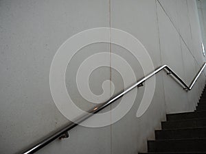 Long shot of silver metal hand railing on a wall beside the stairs in black and white