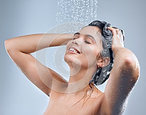 Long showers are therapeutic. a young woman washing her hair in the shower against a grey background.