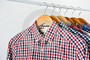 Long sleeve red and blue checkered shirt on wooden hanger over white background