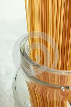 Long spaghetti in glass jar. Ingredient for Italian pasta. Raw food with selective focus