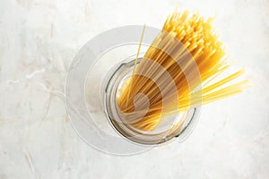 Long spaghetti ready to cook in glass jar, top view. Ingredient for Italian pasta. Raw food