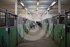 Long stable with numerous paddocks and people in photo