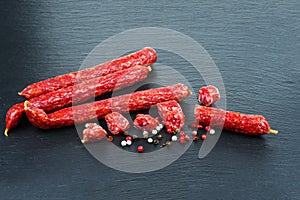 long sticks sousages with red hot peppers on black stone