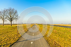 Long straight bike path in a Dutch polder landscape