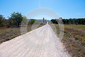 A long straight dusty road along via Francigena in Tuscany, Italy