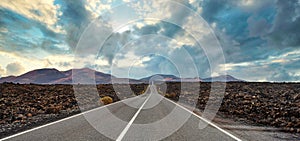 Long straight empty road through volcanic landscape on Lanzarote, Canary Islands