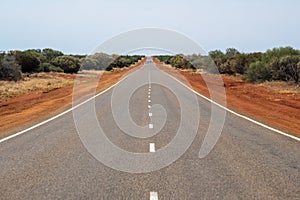 Long straight road leading through dry Australian Bush land photo