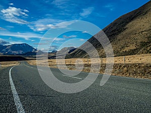 A long straight road leading towards a snow capped mountain in New Zealand