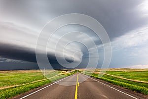 Long, straight road with supercell storm clouds