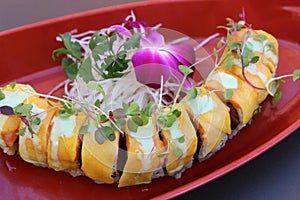 Long sushi roll filled with the freshest ingredients covered in mango slices