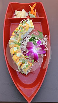Long sushi roll filled with the freshest ingredients covered in mango slices photo