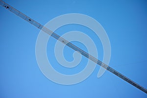 Underside of long suspension footbridge in blue sky